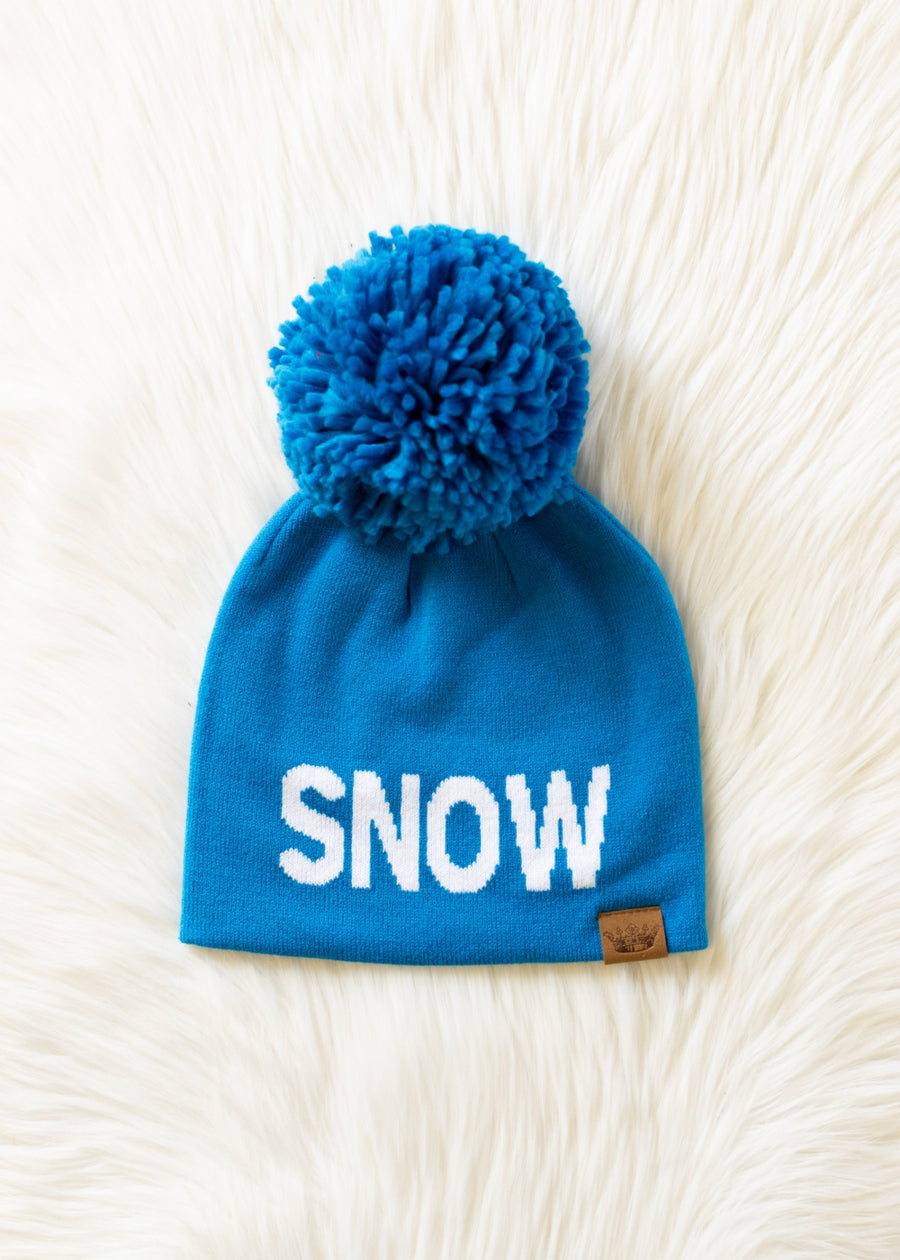 Blue beanie with pom-pom and 'SNOW' text on a white fluffy background