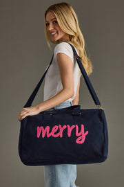 Woman holding a navy blue bag with 'merry' embroidered in pink on a gray background
