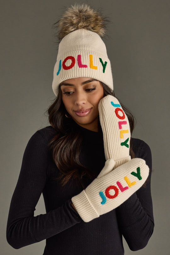 Person wearing a 'Jolly' beanie and mittens with colorful text on a gray background