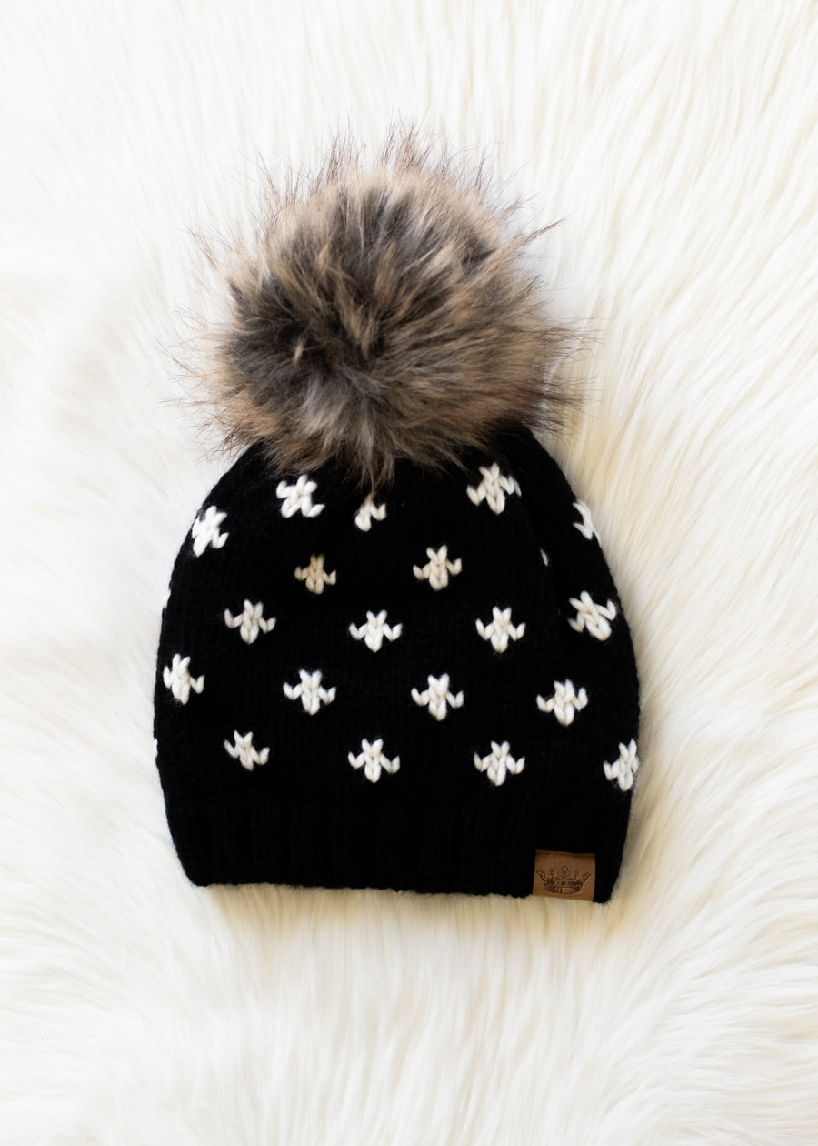 Black beanie with white patterns and a gray pom-pom on a white background