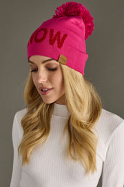 Woman wearing a pink beanie with 'SNOW' text on a gray background