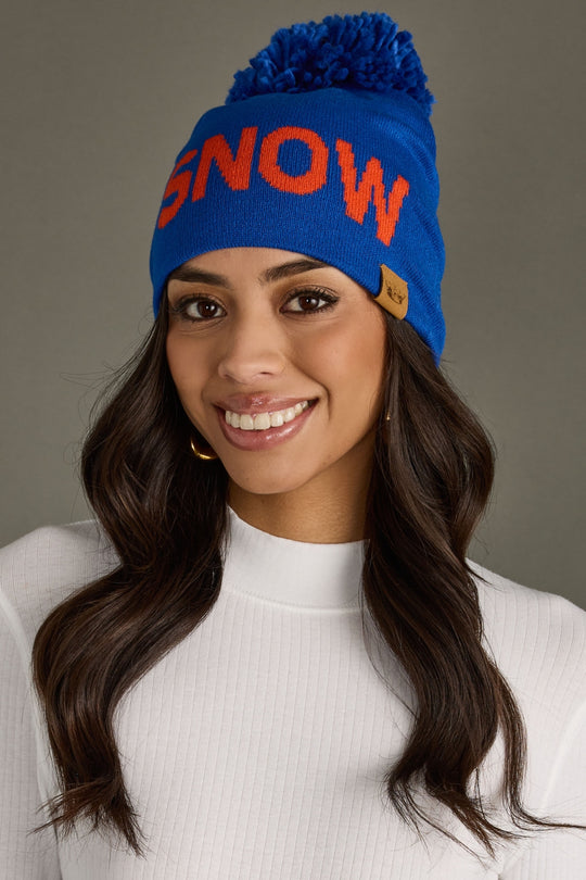 Woman wearing a blue 'SNOW' beanie with a gray background
