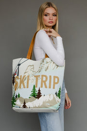 Woman holding a tote bag with 'Ski Trip' and mountain design against a gray background