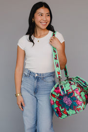 Woman holding a colorful floral bag against a gray background