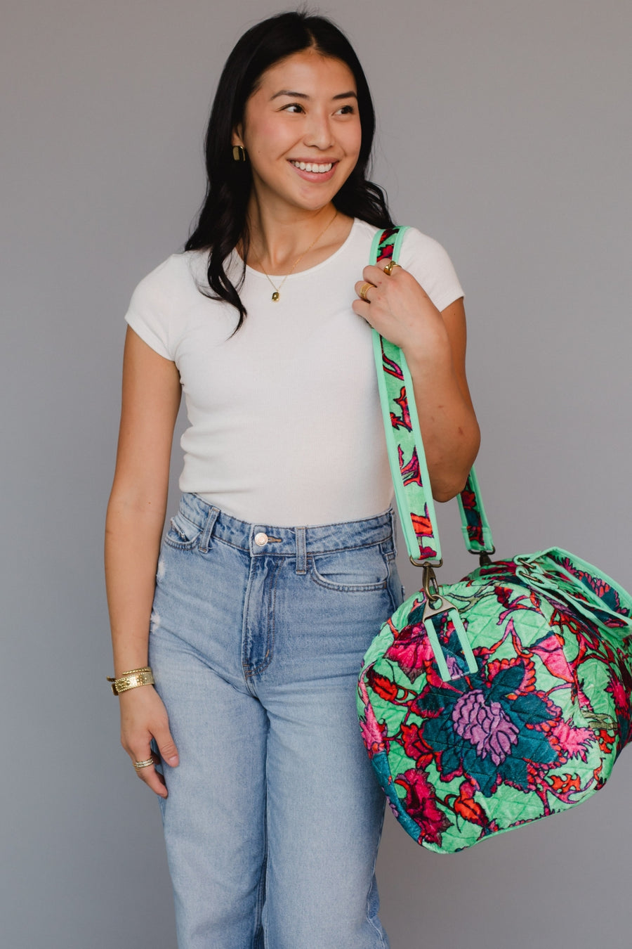 Woman holding a colorful floral bag against a gray background
