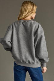 Person wearing a gray sweater and blue pants against a gray background