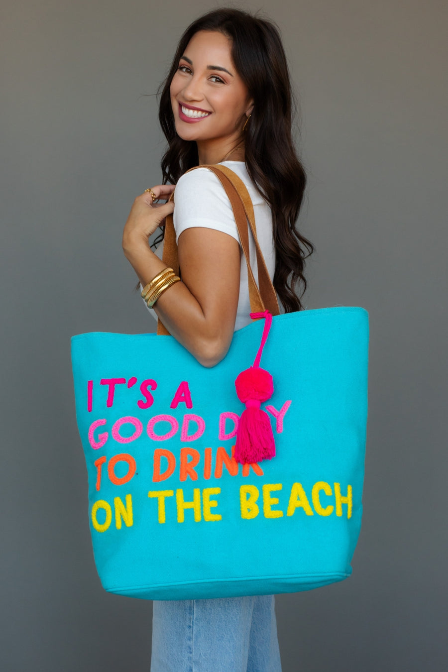 Woman holding a blue tote bag with colorful text against a gray background