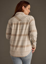 Woman wearing a plaid shirt with a neutral color palette on a plain background
