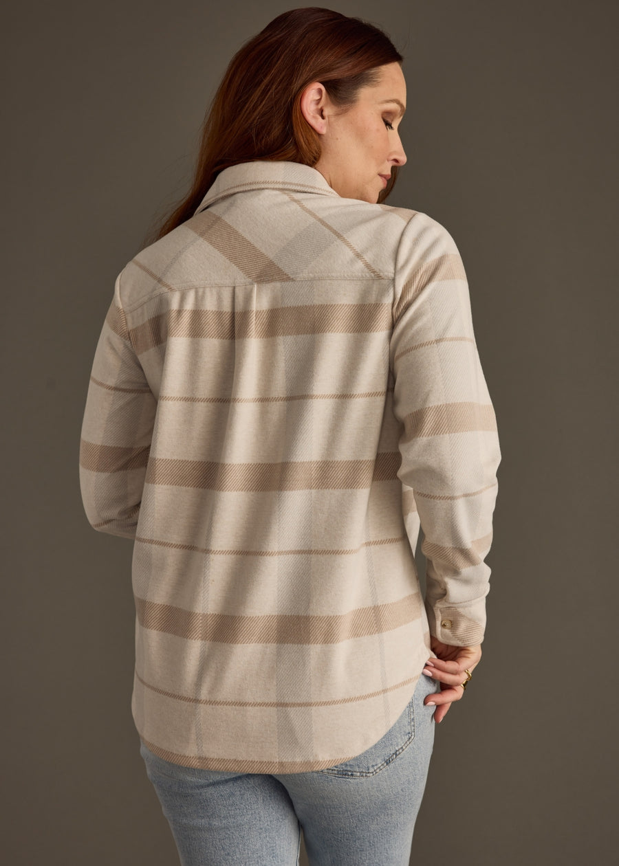 Woman wearing a plaid shirt with a neutral color palette on a plain background