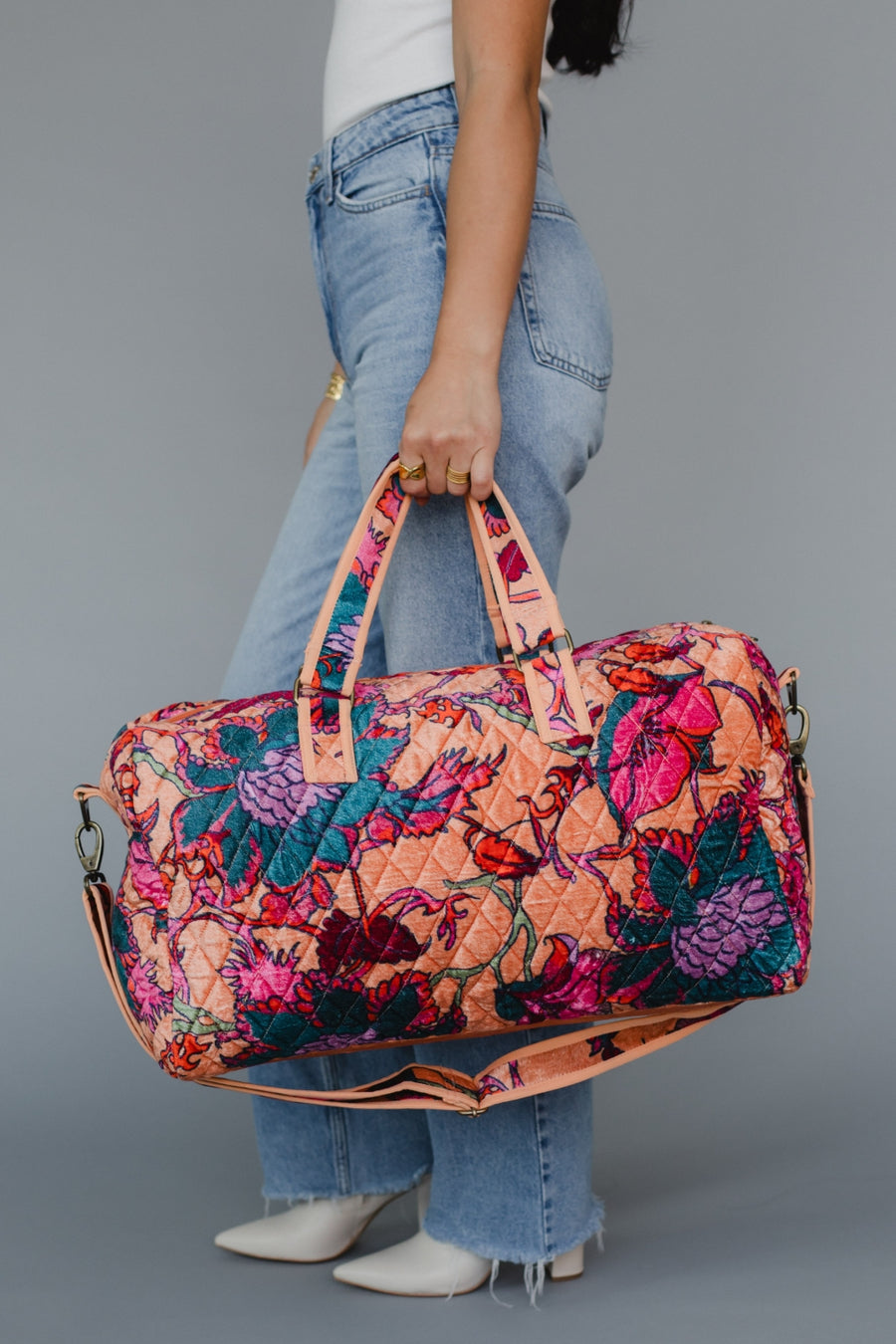 Person holding a colorful floral-patterned bag against a gray background