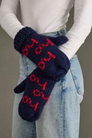 Navy blue mittens with red text worn by a person against a neutral background
