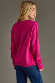 Person wearing a bright pink sweater and blue jeans on a gray background
