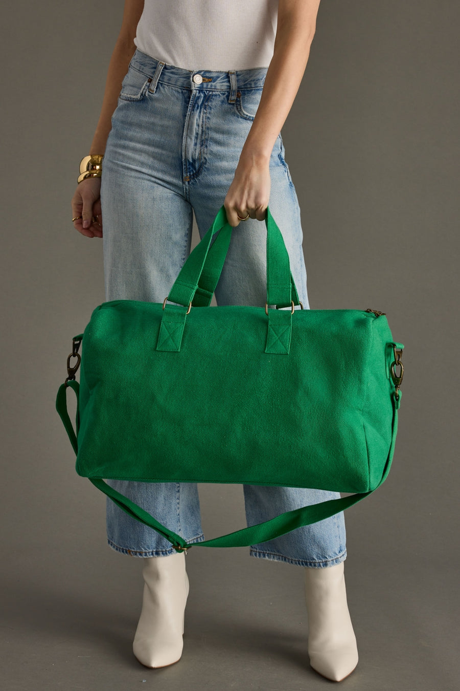 Person holding a green bag against a gray background