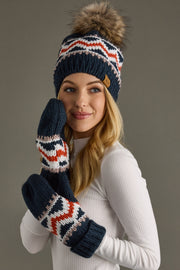 Woman wearing a navy knit hat and gloves with a pom-pom on a gray background
