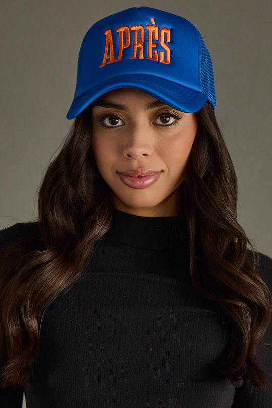 Woman wearing a blue cap with 'APRèS' text on a gray background