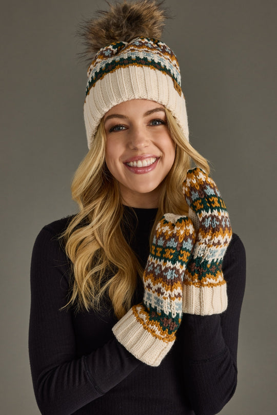 Woman wearing a patterned beanie and mittens with a gray background