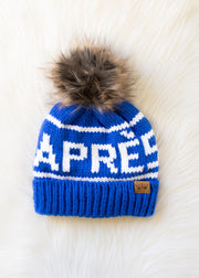 Blue knit beanie with white text and fur pom-pom on a white background