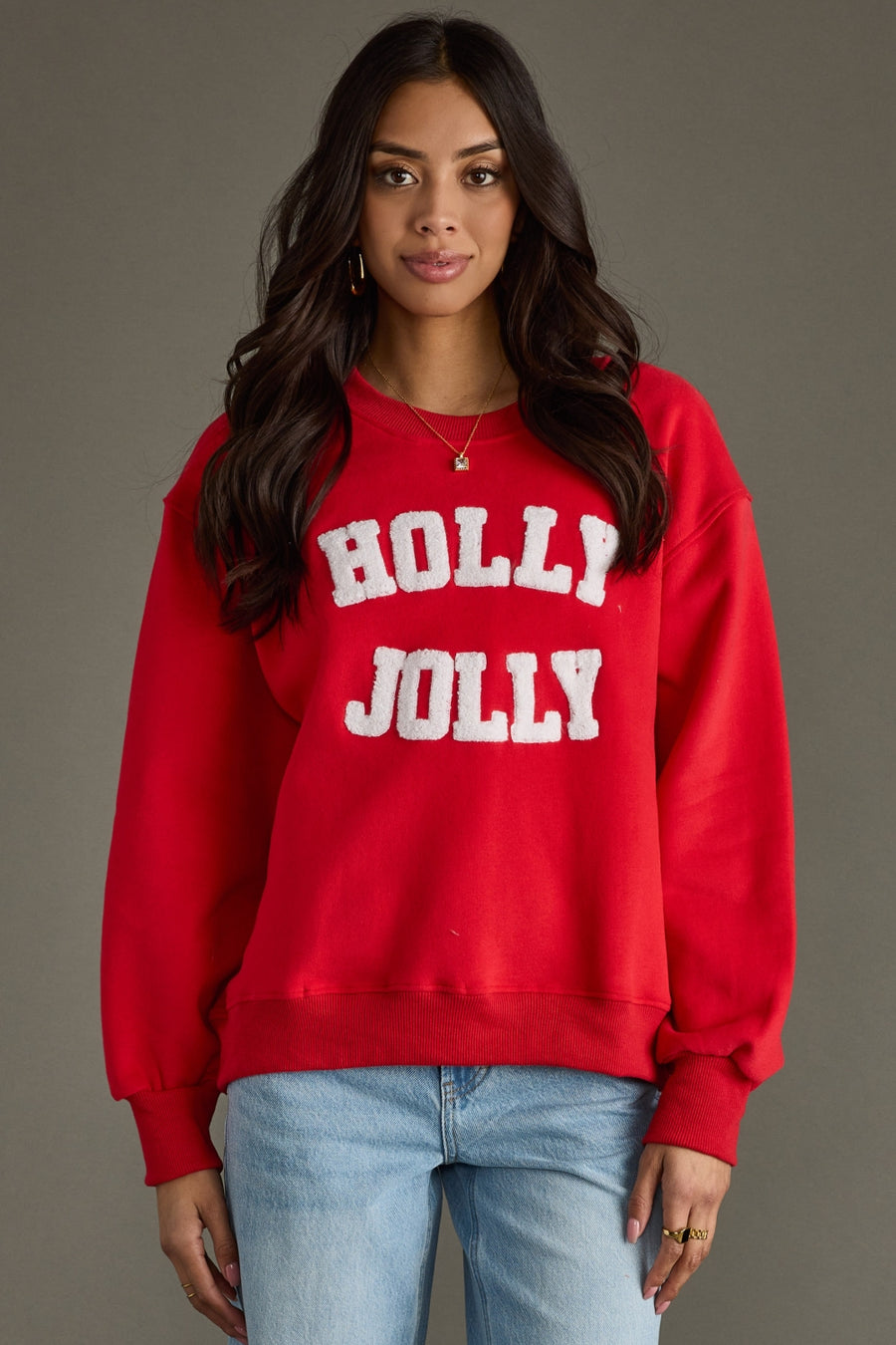 Person wearing a red 'Holly Jolly' sweatshirt against a gray background