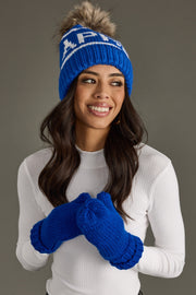 Woman wearing a blue knit hat and gloves with a logo on a gray background
