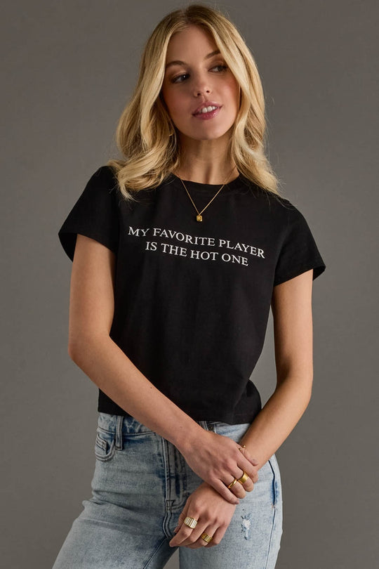 Woman wearing a black t-shirt with text, standing against a gray background