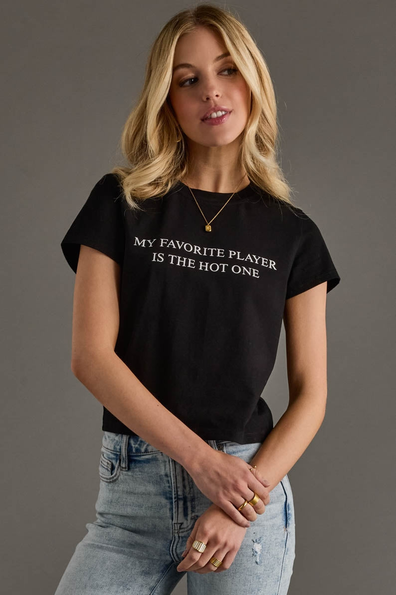 Woman wearing a black t-shirt with text, standing against a gray background