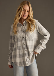Woman wearing a plaid shirt and jeans against a gray background