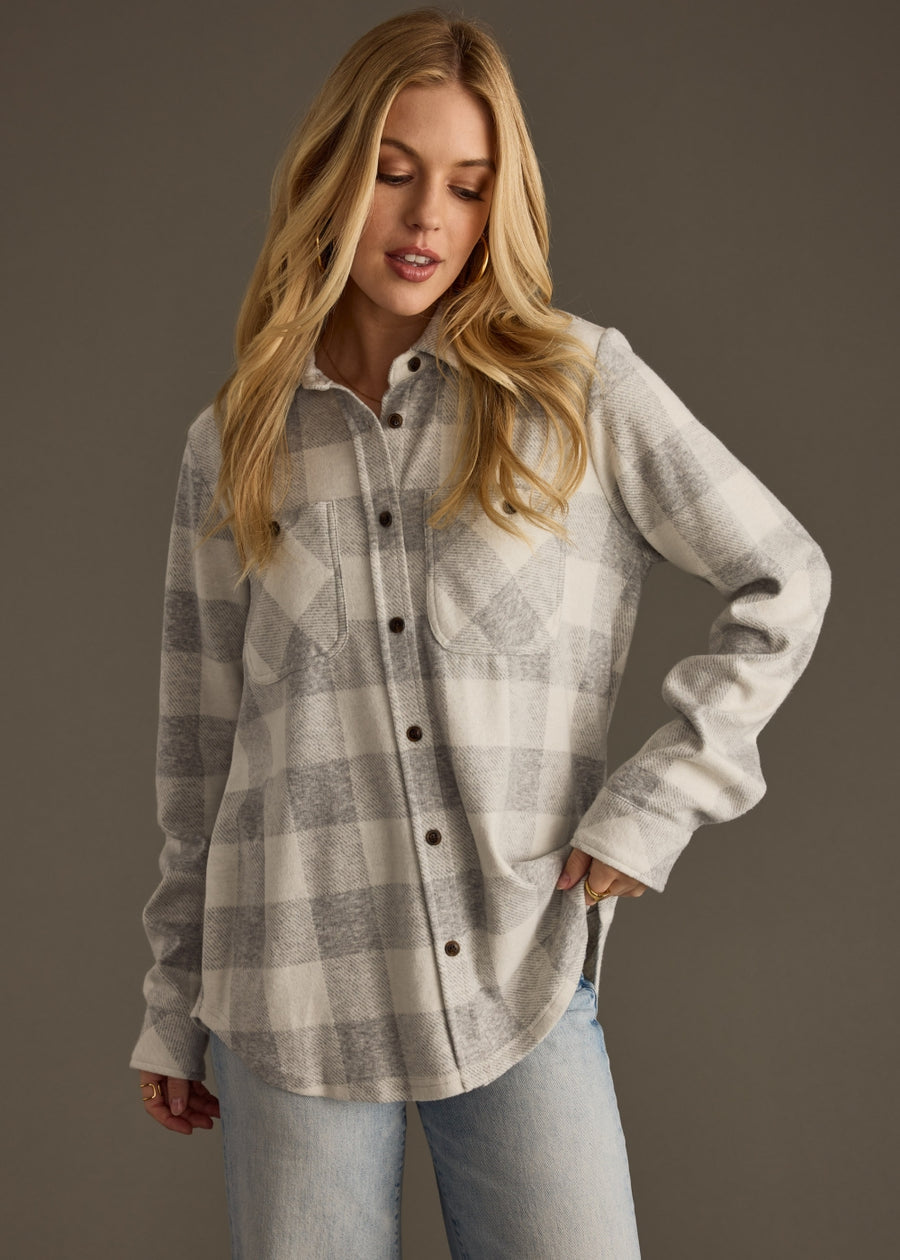 Woman wearing a plaid shirt and jeans against a gray background