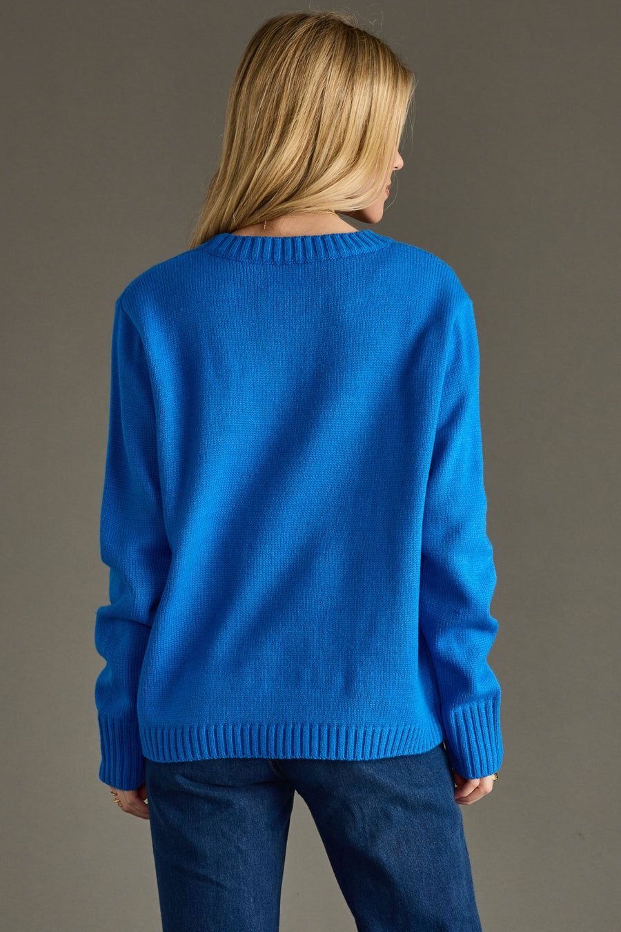 Person wearing a blue sweater against a gray background