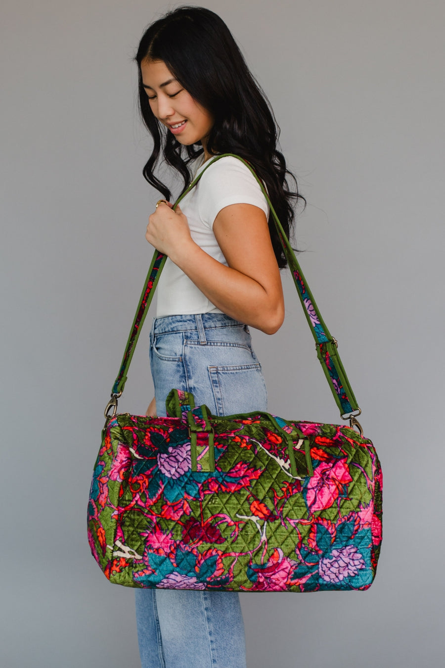 Woman holding a colorful floral-patterned bag against a plain background