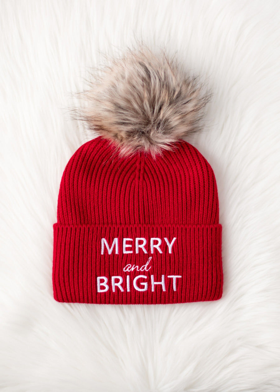 Red beanie with fur pom-pom and 'Merry and Bright' text on a white background