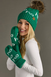 Woman wearing a green knit hat and mittens with text, against a gray background