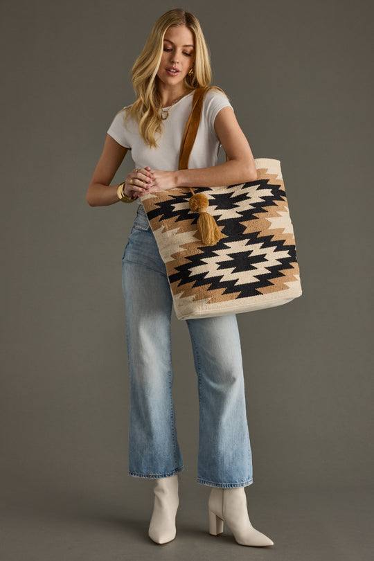 Woman holding a patterned tote bag against a gray background