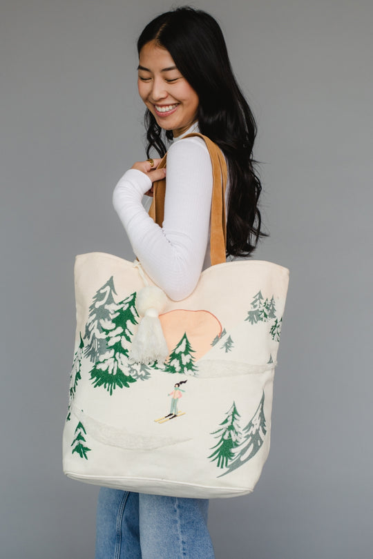Woman holding a tote bag with nature design against a gray background