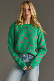 Woman wearing a green sweater with pink text pattern against a gray background