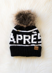 Black and white knit beanie with fur pom-pom on a white background
