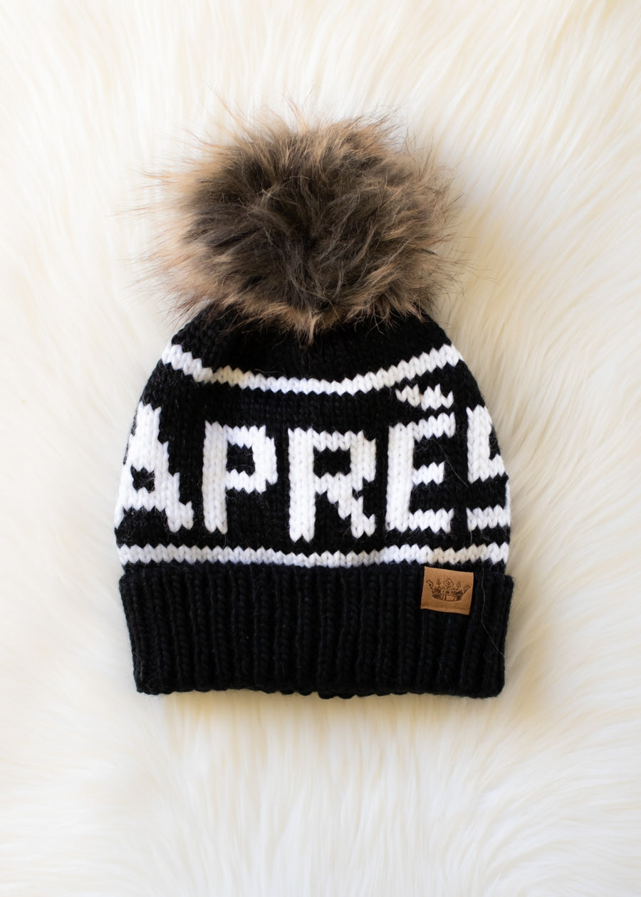 Black and white knit beanie with fur pom-pom on a white background