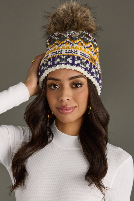 Woman wearing a patterned beanie with a pom-pom against a gray background