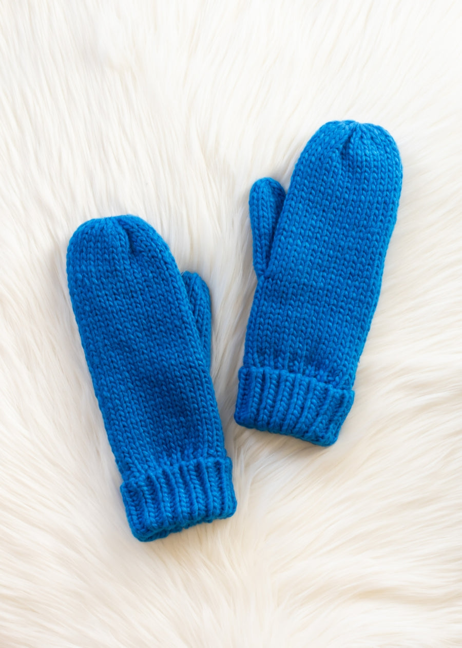 Pair of blue knitted mittens on a white fluffy surface