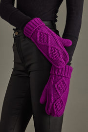 Purple knitted gloves worn by a person against a neutral background