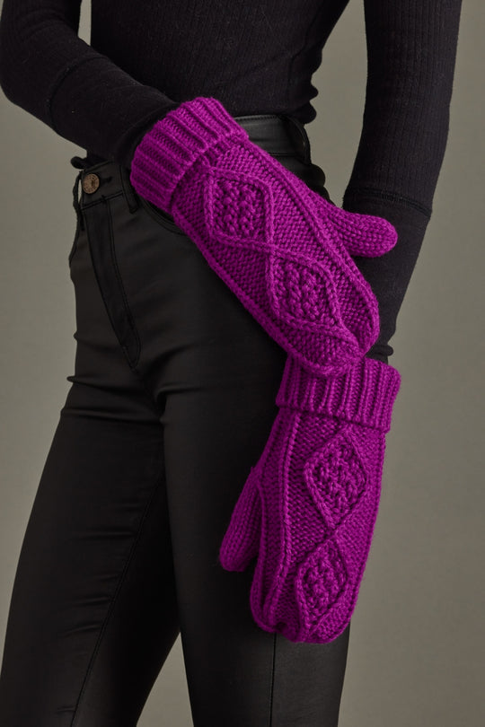 Purple knitted gloves worn by a person against a neutral background