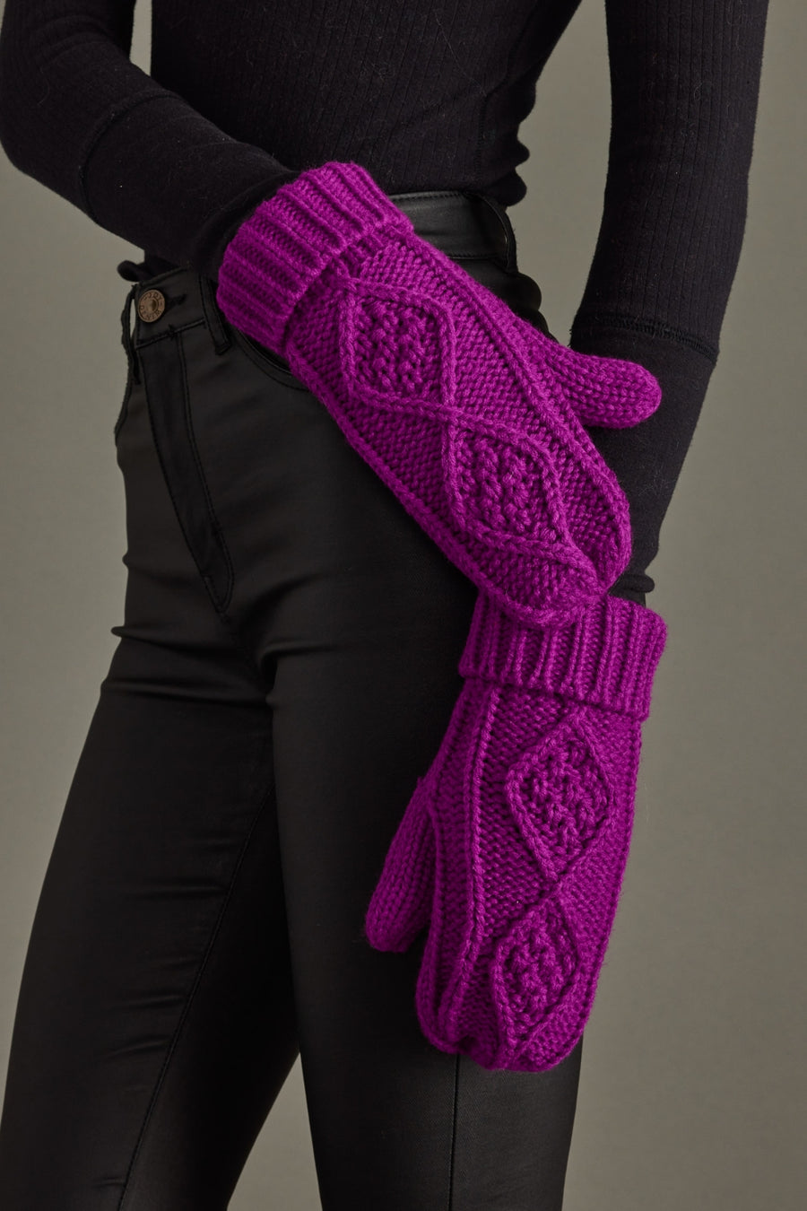 Purple knitted gloves worn by a person against a neutral background