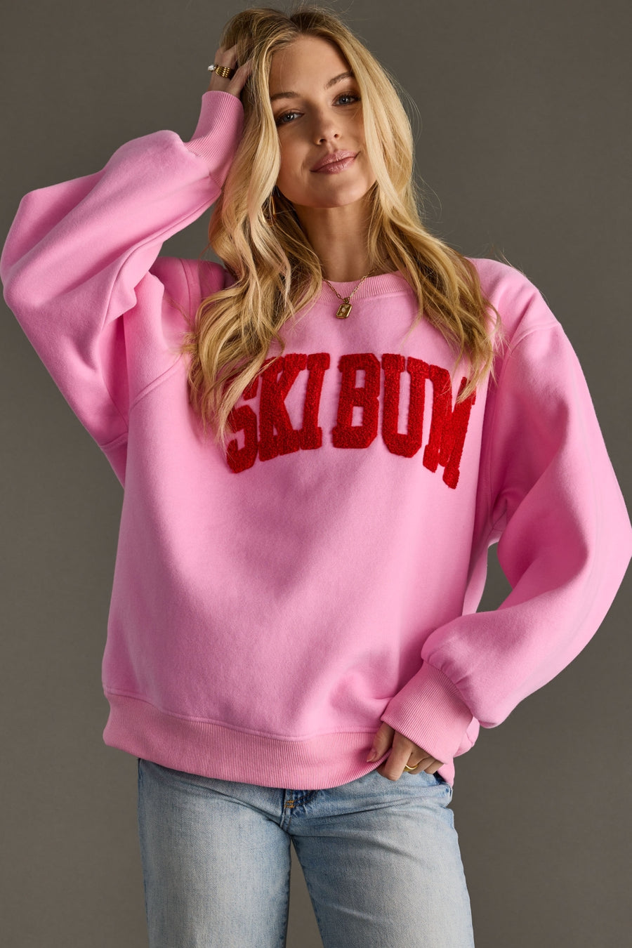 Person wearing a pink sweatshirt with red text on a plain background