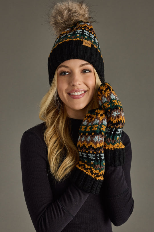 Woman wearing a patterned knit hat and mittens on a gray background