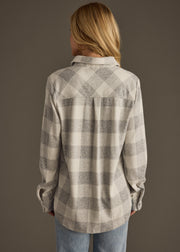 Person wearing a gray and white checkered shirt against a brown background