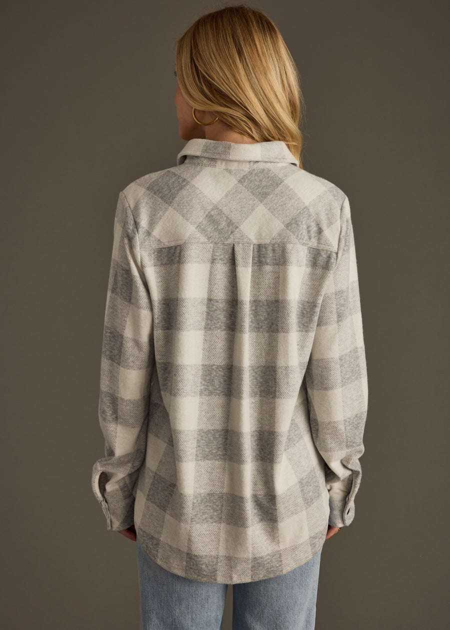 Person wearing a gray and white checkered shirt against a brown background