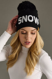 Woman wearing a black beanie with 'SNOW' text against a gray background
