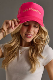 Woman wearing a pink cap with 'DAY DRINKING' text on a gray background