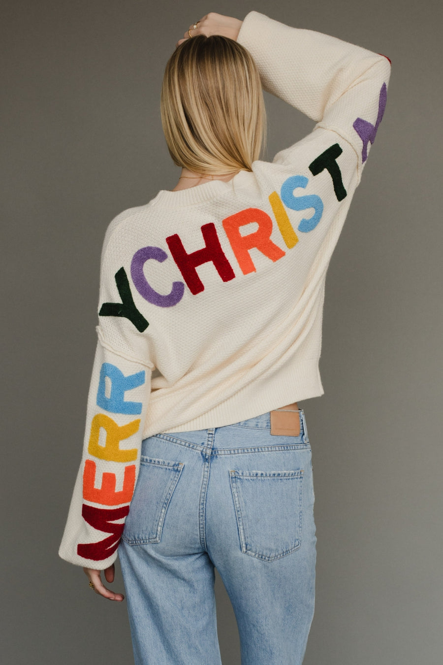 Ivory knit sweater with multicolored 'Merry Christmas' text on the back