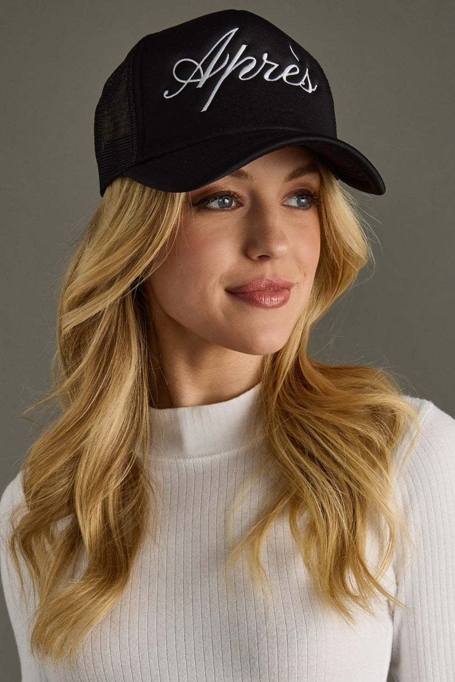 Woman wearing a black cap with 'Apres' text against a gray background