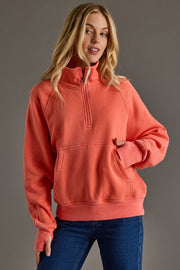 Woman wearing a coral hoodie against a gray background
